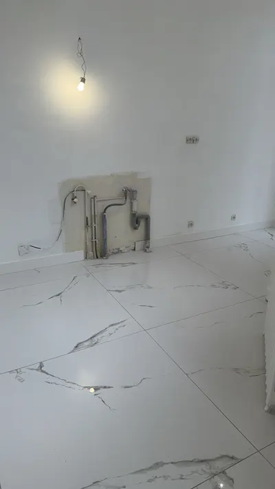 Attentes de plomberie en cuivre sorties du mur dans une salle de bain neuve au sol marbre blanc, réseau AS Depann