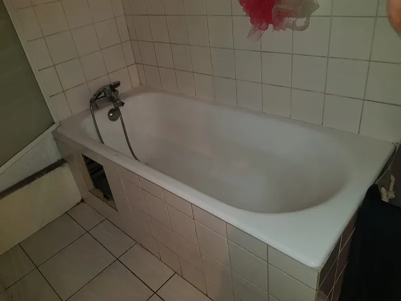 Baignoire ancienne en fonte émaillée dans une salle de bain carrelée blanche avec mitigeur mural, installation d'époque comme il s'en trouve dans les villas de Tassin-la-Demi-Lune, avant rénovation par AS Depann