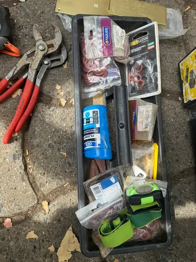 Caisse à outils ouverte avec pince multiprise, clé à molette, joints et pâte à joint, le matériel de base pour les petits gestes de plomberie expliqués dans les guides AS Depann