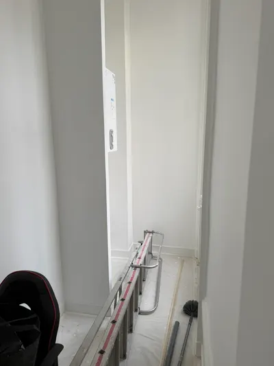 Canalisations d'eau en PER rouge et bleu apparentes le long d'un mur blanc en rénovation, réseau neuf posé par AS Depann