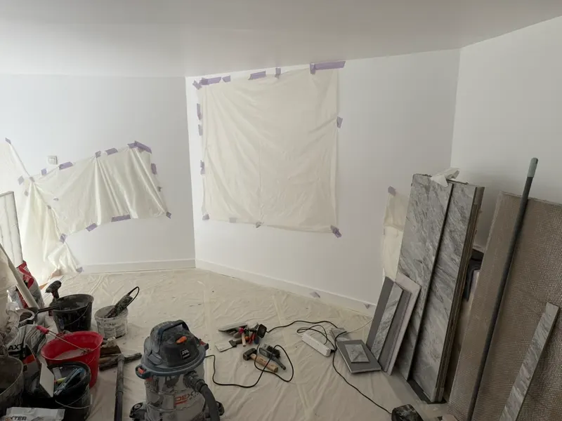 Chantier de salle de bain protégé par des bâches avec carrelage et outils électroportatifs, réseaux posés par AS Depann avant les finitions