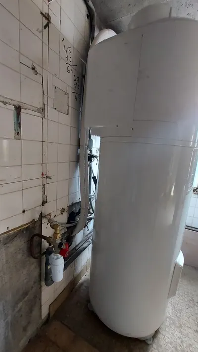 Chauffe-eau électrique dans une cuisine carrelée blanche avec tuyaux cuivre apparents, dépannage pour disjoncteur qui saute par AS Depann