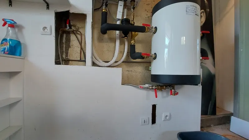 Chauffe-eau électrique mural neuf raccordé avec vannes rouges et tuyaux isolés, ballon posé par AS Depann dans un cellier de Millery