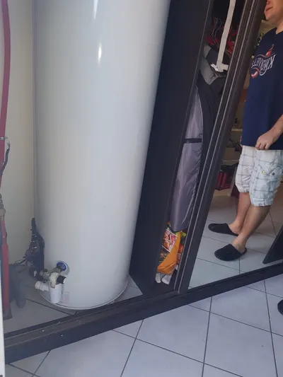 Chauffe-eau vertical installé dans un placard, client à côté sur carrelage blanc, ballon familial posé par AS Depann dans une maison de Charly