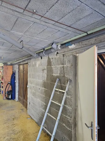 Sous-sol d'immeuble avec collecteur d'évacuation PVC au plafond, intervention AS Depann pour un syndic de copropriété