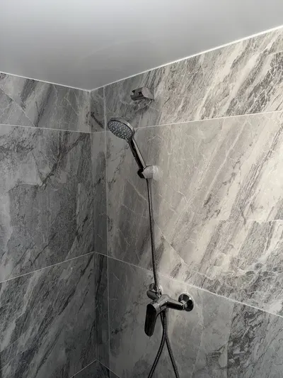Colonne de douche avec douchette dans une douche carrelée marbre gris, installation AS Depann