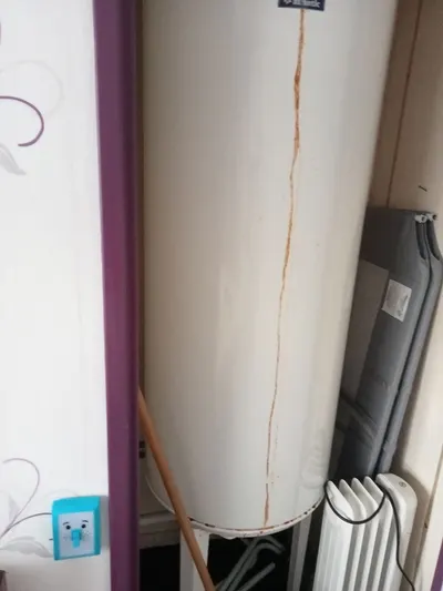 Trace de coulure rouille le long d'un ballon d'eau chaude blanc avec un radiateur à côté, fuite lente de chauffe-eau repérée par AS Depann lors d'une recherche de fuite à Vourles