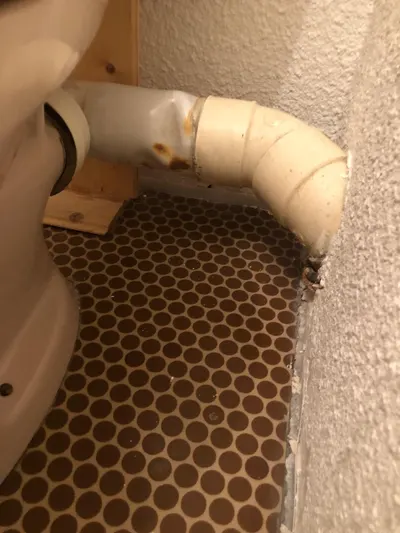 Tuyau d'évacuation PVC ancien avec coude au sol d'une cave d'immeuble, tronçon contrôlé par AS Depann lors d'un débouchage de colonne