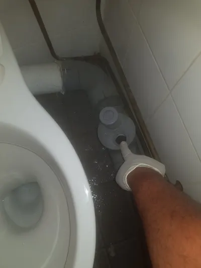 Main tenant un joint de cuvette WC lors d'une réparation de fuite au pied des toilettes par AS Depann