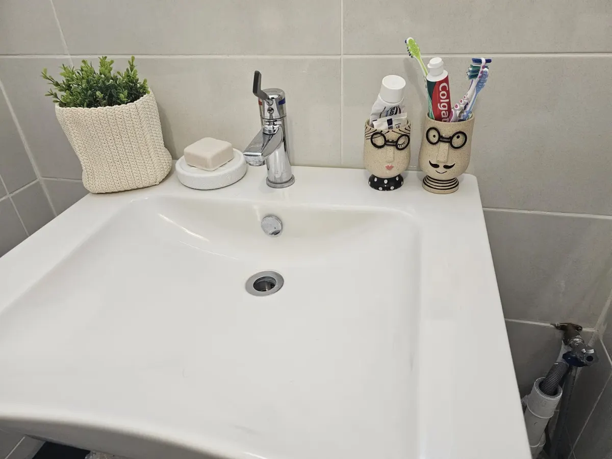 Lavabo blanc avec mitigeur chromé et accessoires de salle de bain, mitigeur du même type dont la cartouche se remplace à l'identique après une fuite à la poignée