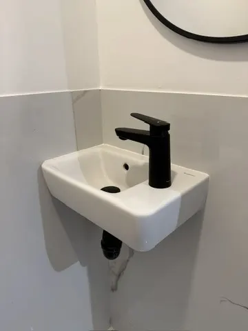 Lave-mains blanc neuf avec mitigeur noir installé dans des toilettes par AS Depann