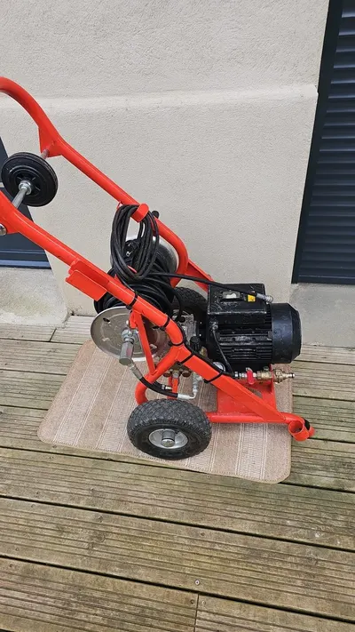 Machine à déboucher électrique rouge à tambour sur roues posée sur une terrasse, matériel de AS Depann pour les canalisations longues des maisons de Millery
