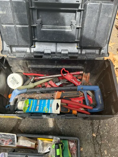 Mallette d'outils du plombier AS Depann ouverte avec clés à griffe, pinces et joints prête pour un dépannage de plomberie