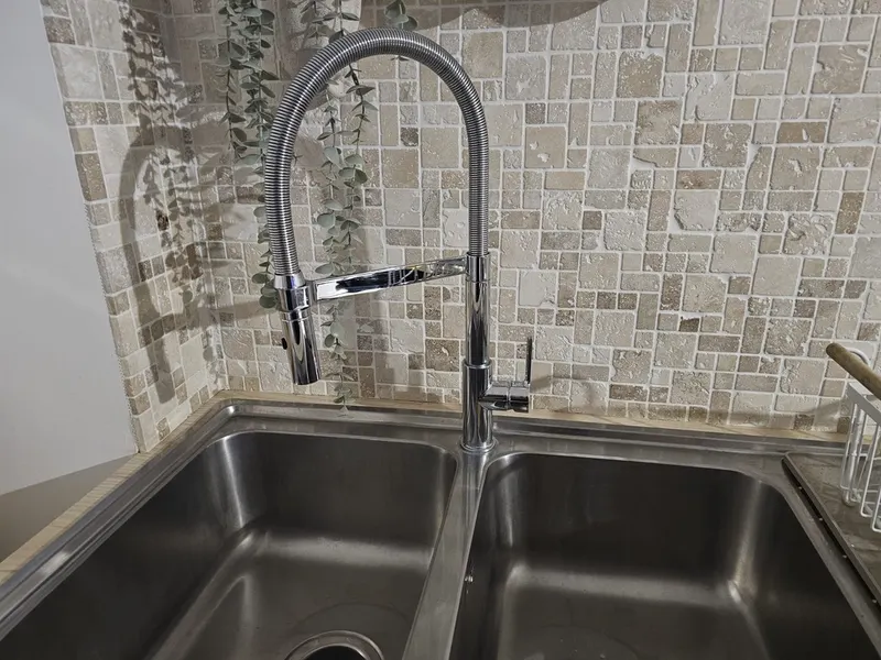 Mitigeur d'évier avec douchette extractible noire installé sur un évier inox à deux bacs par AS Depann