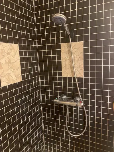 Douche carrelée en mosaïque noire avec mitigeur thermostatique chromé installé par AS Depann