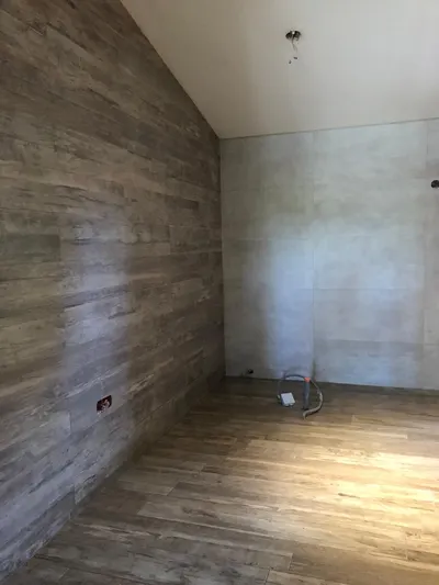 Pièce en cours de rénovation avec murs en parement bois et sol stratifié et attentes de plomberie au sol, attentes posées par AS Depann dans une extension