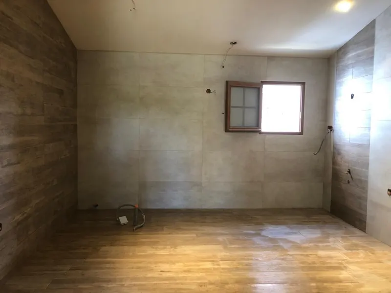 Pièce vide en rénovation avec parquet et fenêtre et attentes de plomberie au mur, réseaux posés par AS Depann avant les finitions d'un chantier