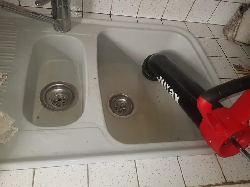 Ventouse à pompe Virax posée sur un évier double bac bouché, premier geste de AS Depann avant le furet dans une cuisine d'appartement lyonnais
