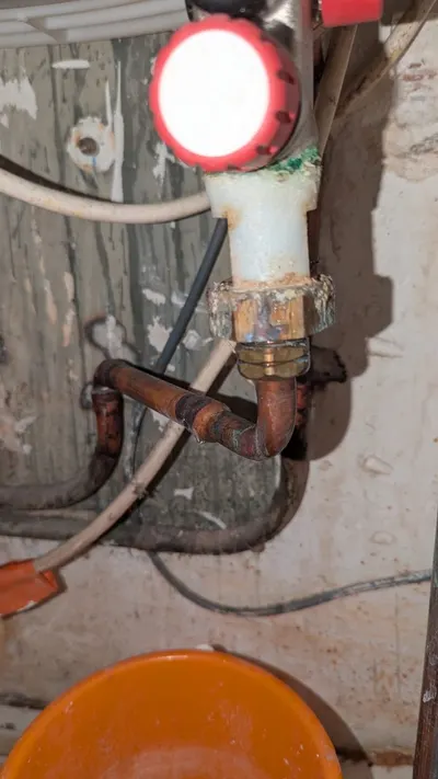 Raccords cuivre soudés et flexible dans un coin sombre avec traces de fuite, jonction ancienne localisée par AS Depann derrière une cloison d'un appartement lyonnais