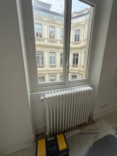 Radiateur en fonte blanc sous une fenêtre d'appartement ancien, émetteur typique des immeubles du sud de Lyon dépannés par AS Depann
