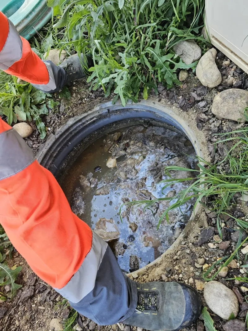 Regard d'eaux usées en fonte ouvert dans un jardin avec eau boueuse, avant hydrocurage de canalisation par AS Depann