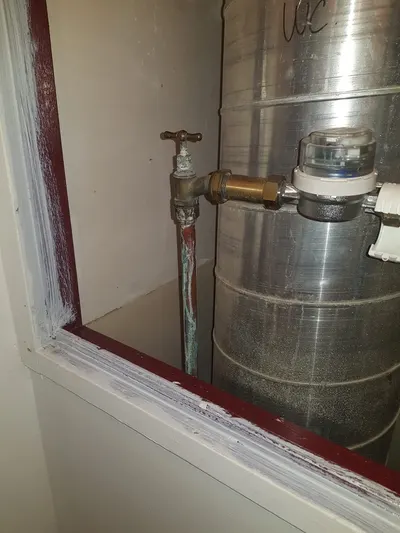 Robinet de puisage laiton et raccords sur un filtre à eau ancien près d'une fenêtre, ancien filtre remplacé par un porte-filtre moderne par AS Depann