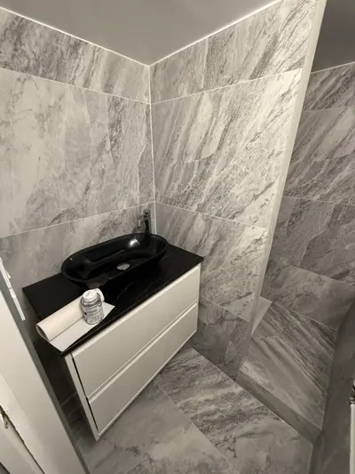 Salle de bain marbre gris avec vasque noire et douche en fond, rénovation complète livrée par AS Depann