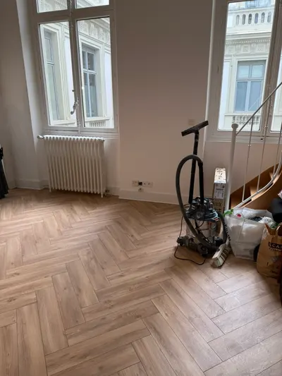Salon avec parquet en chevron, radiateur en fonte et aspirateur de chantier après travaux, radiateur remis en service par AS Depann après un désembouage