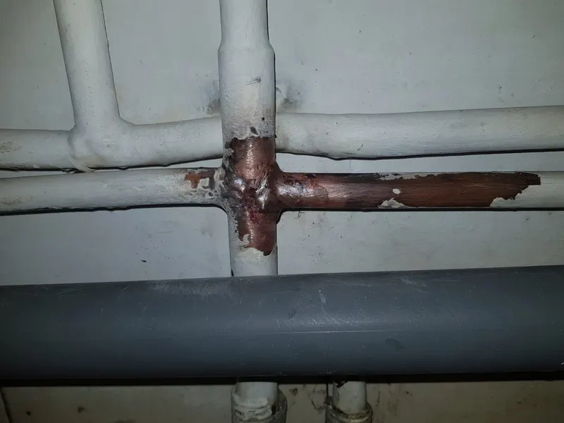 Tuyau cuivre corrodé avec coulure verte sur une canalisation calorifugée en cave, fuite réparée de nuit par AS Depann