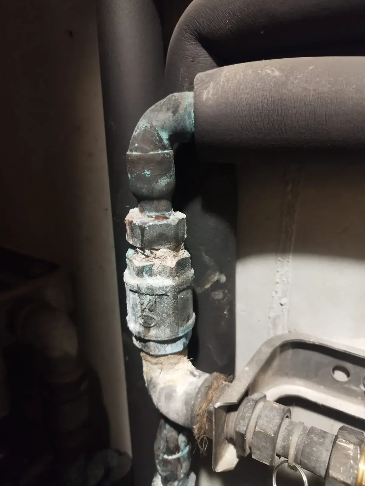 Vanne en laiton oxydée et raccord corrodé sur une canalisation d'eau dans un local sombre, vanne à volant grippée typique des gaines des immeubles haussmanniens de la Presqu'île, remplacée par AS Depann