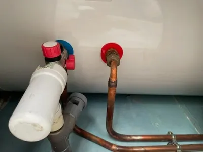 Vannes rouges et tuyaux cuivre raccordés sous un chauffe-eau avec groupe de sécurité blanc, bride contrôlée par AS Depann après un déclenchement du disjoncteur