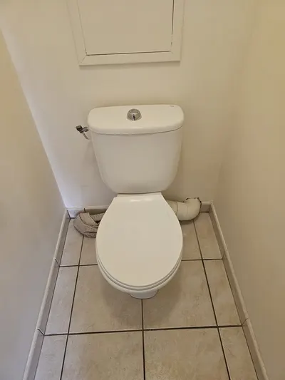 WC à poser blanc dans des toilettes carrelées beige, cuvette libre après un débouchage en trois temps dans un appartement de Pierre-Bénite